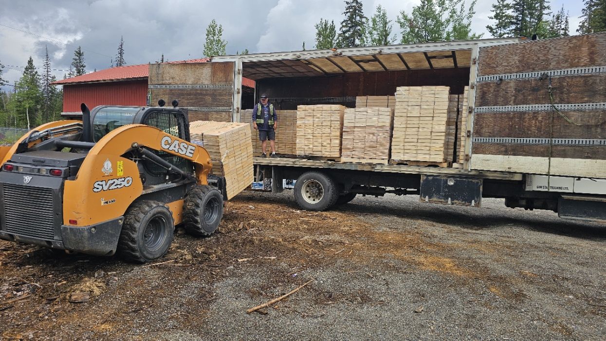 Skid steer loading pallets of core boxes into a truck