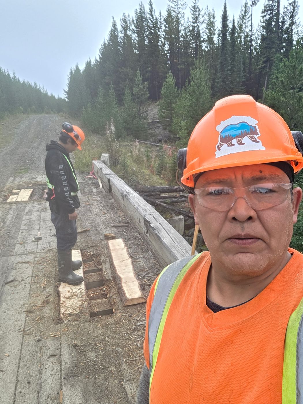 Two crew members repairing bridge decking on a forest road