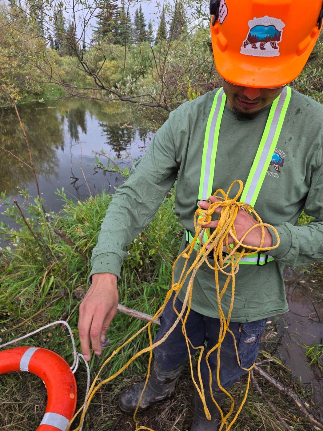 Crew member with rescue rope and life ring beside a creek